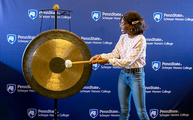 Scholar hitting the gong after submitting their honors thesis