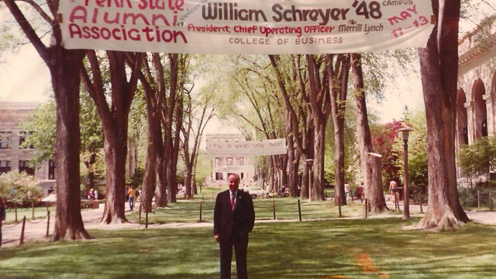 William Schreyer posing under a banner on campus